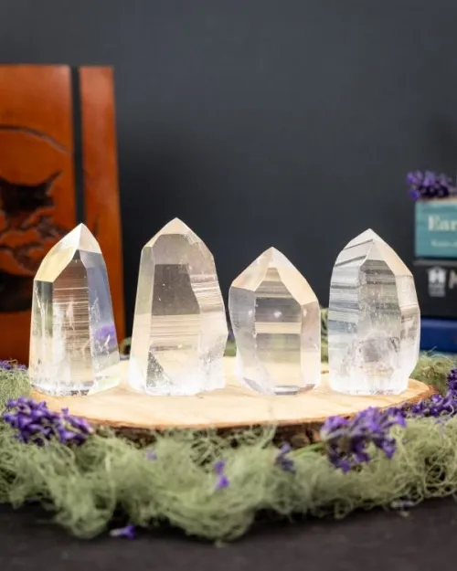 Hand comparing polished versus raw quartz points on a pillow surface