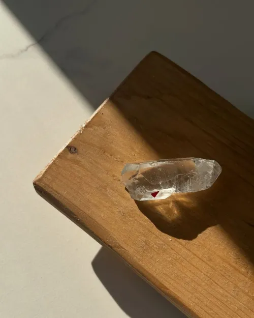 Hand holding quartz and amethyst necklace over velvet pouch