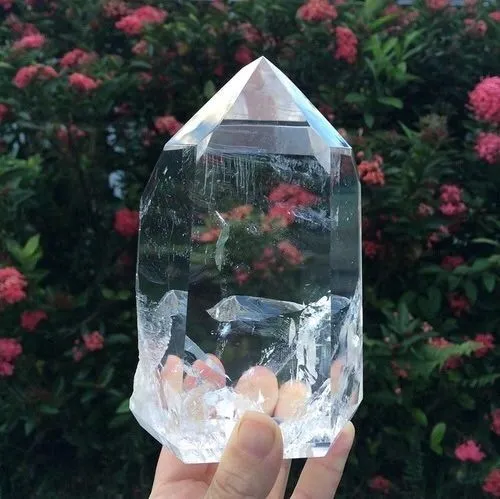 Person meditating with clear quartz while sunset light passes through